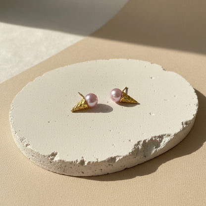 Findingyoyo Gelato earrings featuring pink pearl scoops on textured gold ice cream cones on a stone display base.