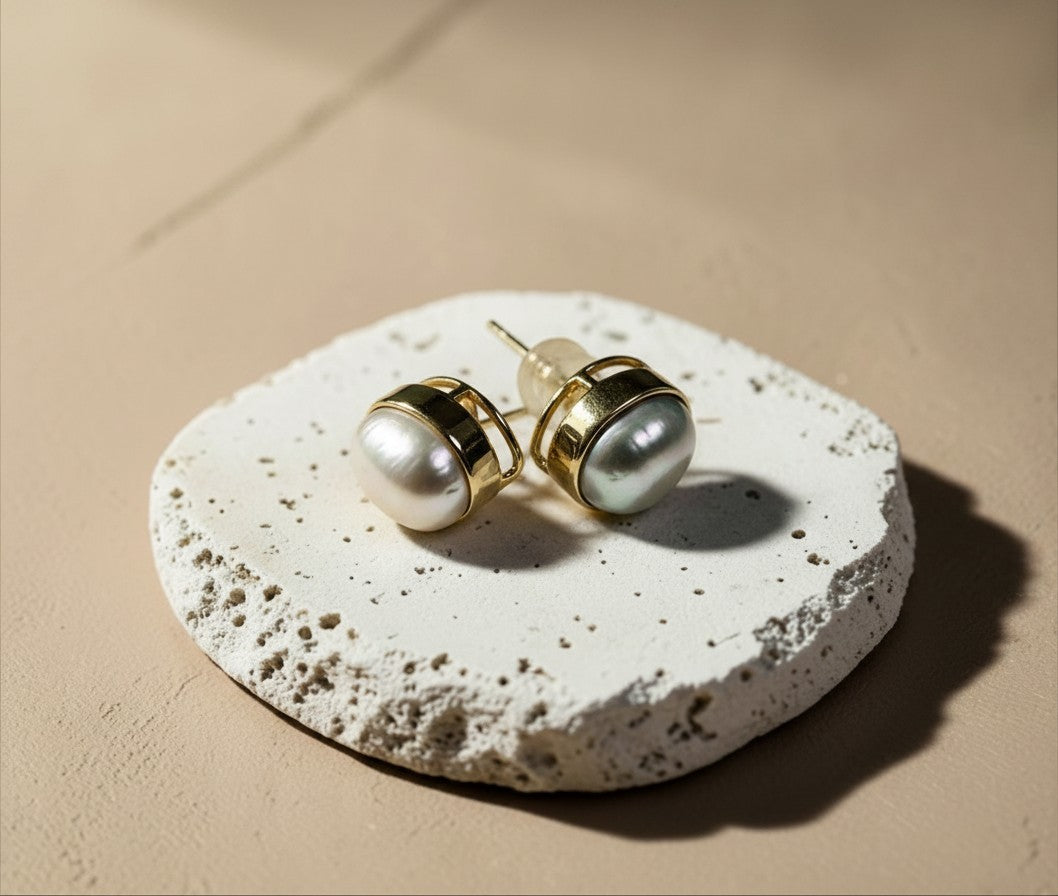 Findingyoyo Waltz earrings featuring unique keshi pearls in solid 18K gold bezel settings on a textured stone base.