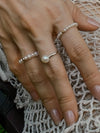 Hand wearing pearl rings on crochet texture - Ancient Stones Modern Soul